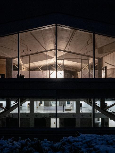 Aussenansicht bei Nacht; Blick in das Schulgeschoss im ersten Obergeschoss und die darunterliegende Dreifachturnhalle; Baustelle Dezember 2020, Foto: E2A